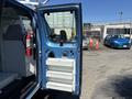 A 2008 Ford E-350 van with an open side door revealing storage compartments inside