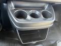 Black cup holder console with three circular slots and an open storage compartment below