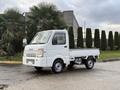 A white 2009 Suzuki Carry mini truck with a flatbed and compact design parked on a concrete surface
