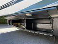 A metallic storage compartment of a 2000 Ford Motorhome with open doors revealing interior space containing a coiled cable and a blanket