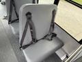 A gray fabric seat with a seatbelt secured to it located inside a Chevrolet Express van