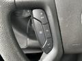 Close-up of a steering wheel control panel featuring buttons for cruise control settings on a 2023 GMC Savana