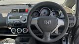 Interior view of a 2006 Honda Fit showing the steering wheel dashboard with gauges and control panel for audio and climate settings