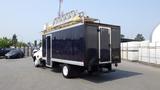 A 2013 Hino 268 truck with a large black box cargo area and a ladder on top parked in a lot