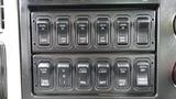 A series of control switches and buttons on the dashboard of a 2012 International 7400 truck including lights and locking mechanisms