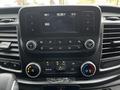 Dashboard of a 2023 Ford Transit featuring a digital display radio, climate control buttons, and various knobs for audio and temperature settings