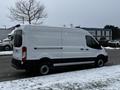 A white 2021 Ford Transit van parked on a snowy street with a simple design and large cargo space