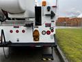 A 2013 International DuraStar utility truck with a yellow hydraulic access panel and safety lights on the rear side