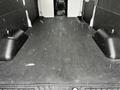 A 2021 Ford Transit van with a spacious, empty interior featuring a dark rubber floor and two raised wheel wells on either side