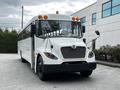 A white 2015 Spartan school bus with black wheels and a distinctive front grille featuring a circular emblem