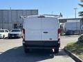 A white 2016 Ford Transit van is shown from the rear with a ladder rack on the roof and no visible markings or windows in the back doors