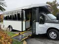 A 2019 Chevrolet Express bus with an open door and a wheelchair ramp extended for accessibility