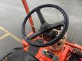 A close-up of the steering wheel and control panel of a 2010 Kubota F3680 featuring a black steering wheel and various controls in an orange and beige color scheme