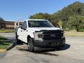A white 2018 Ford F-150 pickup truck parked in a clearing showcasing its front view with a bold grille and headlights