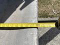 A tape measure extended across a metal surface showing measurements in inches and feet