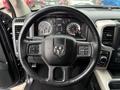 A 2018 RAM 1500 steering wheel with a black leather cover featuring controls and the RAM logo in the center
