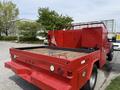 A red 2013 Ford F-550 with a flatbed and a utility box attached to the rear