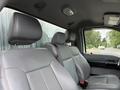 The image shows the interior of a 2015 Ford F-350 SD featuring gray leather seats with headrests and seatbelts attached.