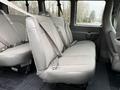 A gray bench seat with seatbelts inside a 2023 GMC Savana van