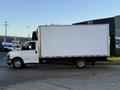 A white 2015 GMC Savana box truck is parked with its side facing the viewer featuring a large blank cargo area and a sturdy truck bed