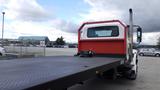 A 2015 International DuraStar 4300 flatbed truck with a red cabin and a large flat cargo area visible from the rear angle