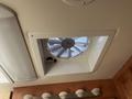 A ceiling vent fan with a circular design and blades visible through the mesh cover in a recreational vehicle interior