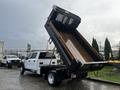 A 2021 Ford F-550 dump truck with the bed elevated and tilted at an angle for unloading materials