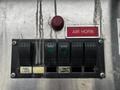 A control panel featuring five black switches and two labeled buttons for air horn and panel lights on a metallic surface