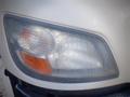 Close-up of the headlight of a 2013 Hino 308 with a clear lens and a small orange indicator light