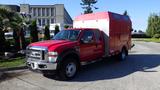 A red 2010 Ford F-550 truck with a large enclosed cargo area in the back has dual rear wheels and a prominent front grille