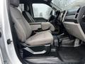 Interior view of a 2021 Ford F-550 showing the driver's side seat and console with gray upholstery and storage compartments