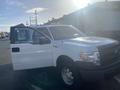 A 2013 Ford F-150 pickup truck with a white exterior and open driver's side door