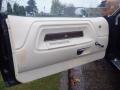 A 1974 Dodge Challenger door panel featuring a white leather finish with wooden trim and chrome handles