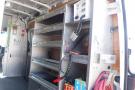 A 2012 Mercedes-Benz Sprinter interior with metal shelves and various tools and equipment along the side wall