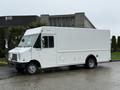 A white 2012 Ford Econoline van with a boxy shape and side door parked on a wet surface