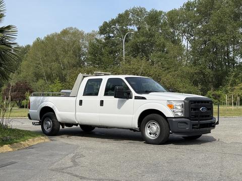 A white 2011 Ford F-350 Super Duty pickup truck with a flatbed and side steps parked on a driveway