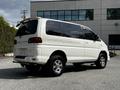 A white 2003 Mitsubishi 7 Passenger Van with a distinctive design featuring a rounded rear and alloy wheels
