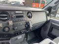 Interior dashboard of a 2015 Ford F-250 SD featuring controls for audio and climate systems along with storage compartments and a gear shifter