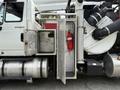 A side view of a 2014 International 7500 showing an open metallic compartment containing a fire extinguisher attached to the vehicle's main structure