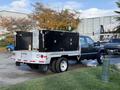 A 2008 Ford F-550 with a flatbed and black storage boxes on the back parked on a paved surface