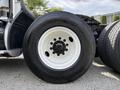 Close-up of a 2012 Volvo VNL truck tire with a white rim and large tread pattern bolted onto the axle