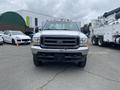 A 2003 Ford F-450 SD with a silver exterior is facing the camera showing its large front grille and headlights