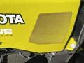 A close-up view of a yellow Kubota F3990 tractor featuring a mesh grill panel and the Kubota logo prominently displayed on the side