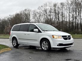 A white 2017 Dodge Grand Caravan parked with its front angled slightly towards the viewer showcasing its distinct grille and headlights