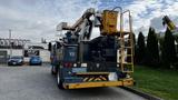 A 2009 International 4300 bucket truck with a yellow aerial work platform mounted on the back and multiple storage compartments along the sides