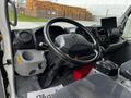 The interior of a 2018 Hino 195 featuring a black steering wheel dashboard controls and a gear shift with an attached monitor