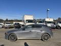 A gray 2023 Mazda MAZDA3 hatchback with a sleek design and black wheels is parked on a lot with other vehicles in the background