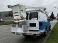 A blue and white 2009 Ford Econoline van equipped with a utility lift on the roof and a metal platform at the back