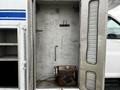An open compartment of a 2006 GMC C5000 showing empty shelves on one side and a small rusty tank on the floor