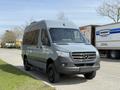 2019 Mercedes-Benz Sprinter van in gray parked on a street with a front view showcasing its distinctive grille and modern design